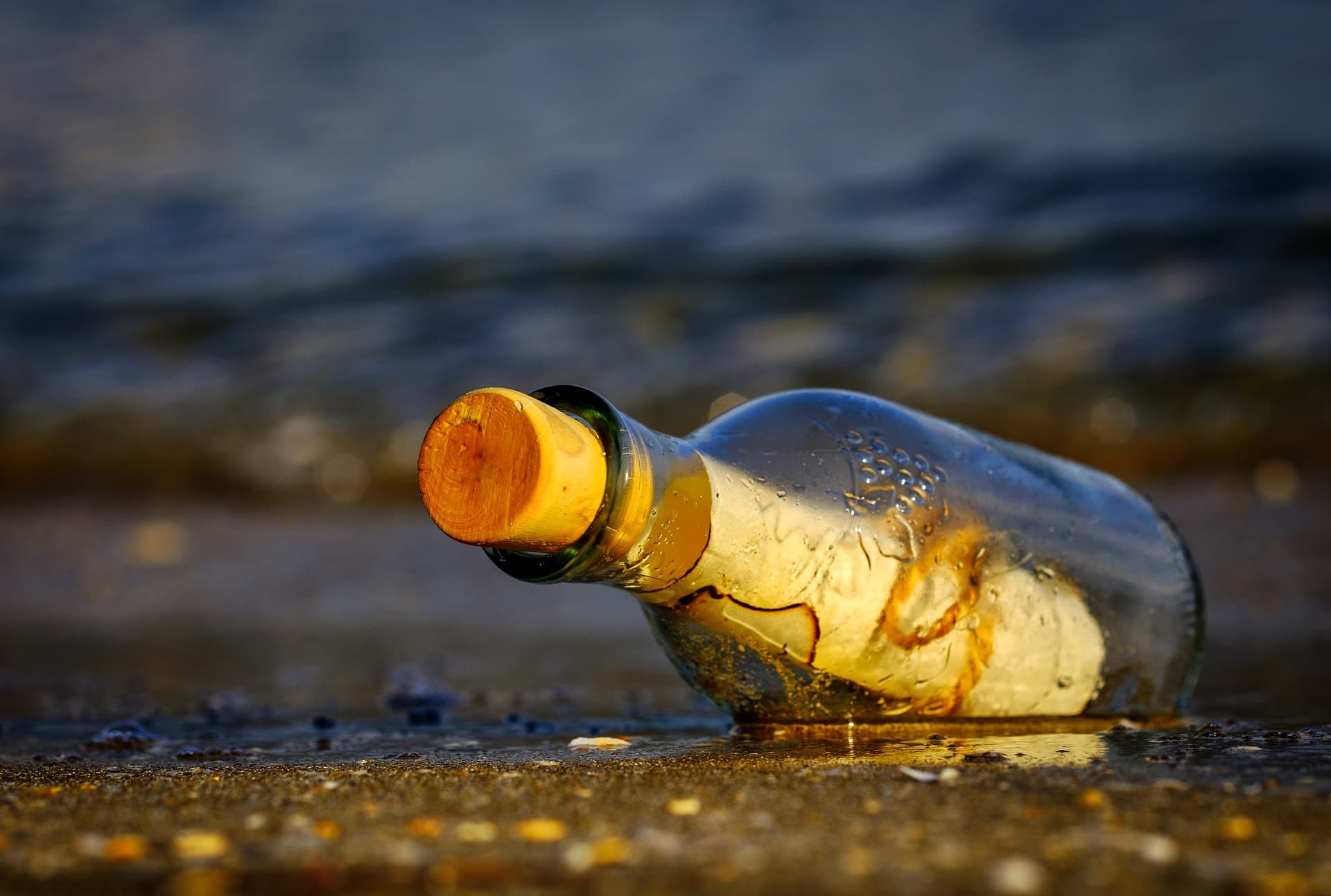 Flessenpost op het strand bij zonsondergang