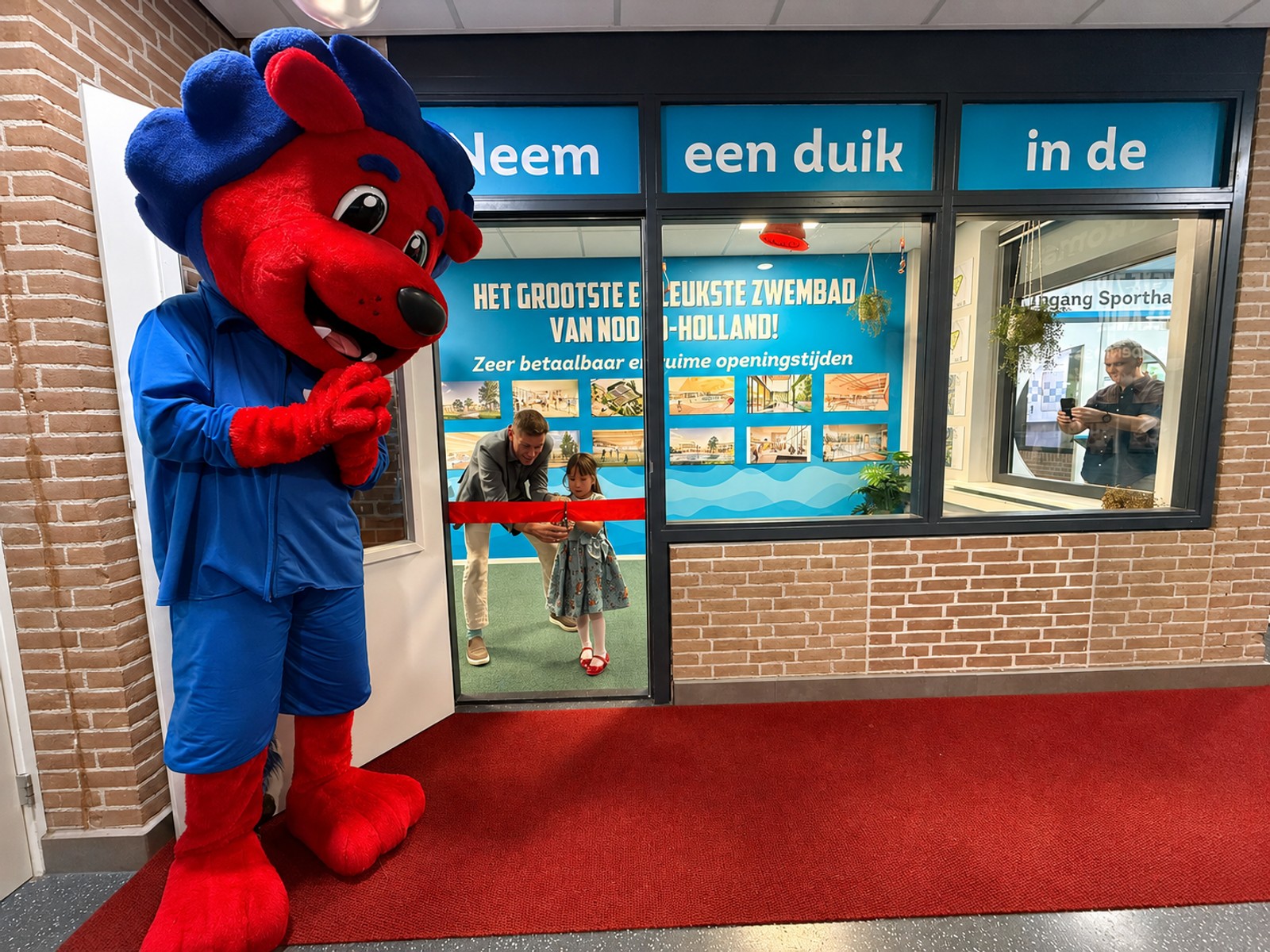 Onder toeziend oog van mascotte Freddy Fit openen Mayla Ruitenberg en Eddy Bakker samen de expositieruimte van het toekomstige zwem- en sportcomplex Hoornse Vaart 1.jpeg