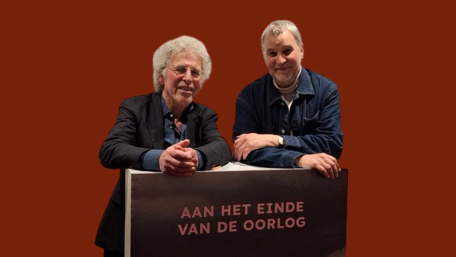 Twee personen achter podium met boektitel, oranje achtergrond